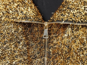 Detail of metallic golden thread fabric and silver zipper on a chic bomber jacket