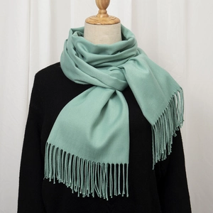 Detail of mint green cashmere-feel scarf featuring thick texture and long tassel edges