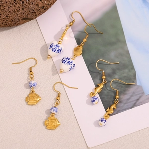 Detail of 18K gold hooks and blue floral ceramic fish pendants on elegant earrings