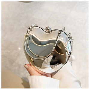 Detail of silver heart-shaped acrylic bag with mirror finish and metal chain strap