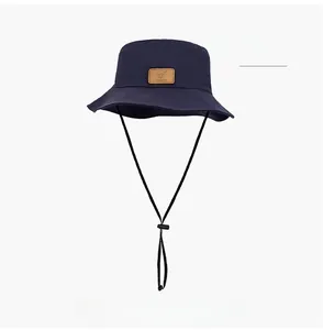Detail of navy blue sun hat featuring a leather patch and adjustable windproof chin strap