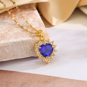 Detailed close-up of heart-shaped blue sapphire pendant with diamond halo on gold chain