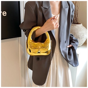 Chic gold crescent acrylic handbag with metallic finish and gold chain strap on model