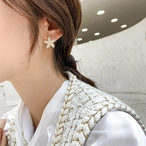 Elegant gold starfish stud earrings with pearls shown on a model for a stylish look