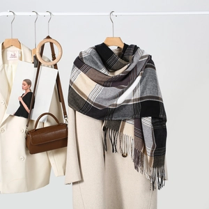 Classic checkered scarf with fringe on a beige coat with accessories in a soft studio setting