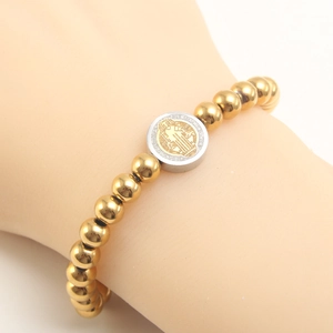 18K gold beaded bracelet featuring a St. Benedict medal pendant on model's wrist