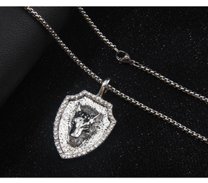 Macro shot of silver wolf head shield pendant with box chain and sparkling zircons