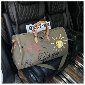 Detail of olive green canvas travel bag with colorful graffiti and brown leather handles