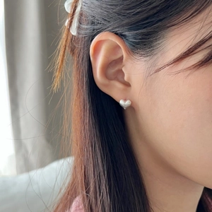 Close-up of minimalist brushed 925 sterling silver heart studs worn on ear model