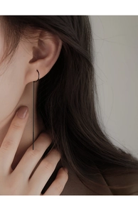 Detail of a minimalist black metal tassel earring worn by a model for a chic look