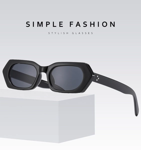 Detail of bold black hexagonal sunglasses featuring silver rivet accents on side temples