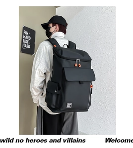 Close-up of black waterproof backpack showing orange zippers and side logo tag details