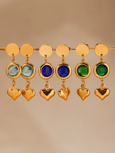Detalle de pendientes de corazón dorados con cristales brillantes en azul y verde
