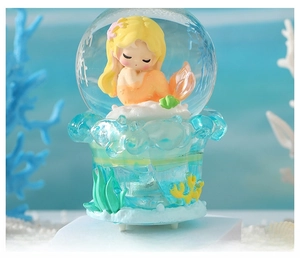 Detail of mermaid snow globe with glowing light and blue water wave resin base