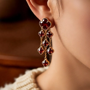 Close-up of vintage 18k gold-plated tassel earrings with red glass clover motifs