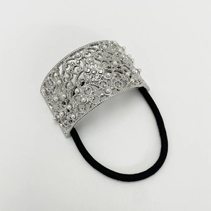 Detail of silver hollow floral metal charm with pearls and rhinestones on black hair tie