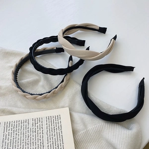 Set of 4 woven braided sponge headbands in black and beige displayed on a book