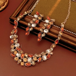 Detail of vintage gold necklace set with amber teardrop crystals on a textured background