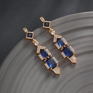 Macro shot of luxury gold-plated geometric earrings with blue gemstones and zircons