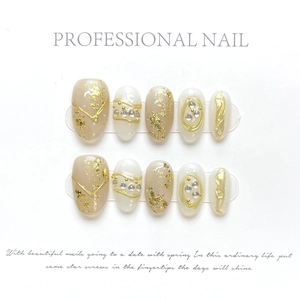 Detail of luxury press-on nails with gold foil and rhinestones in nude tones