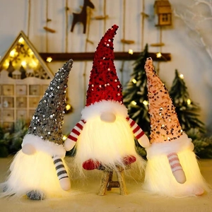 Three Christmas gnomes with LED lights and sequin hats on a cozy wooden holiday background