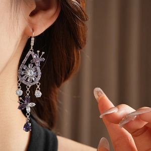 Macro detail of silver floral earring with purple zircon butterfly and teardrop tassel
