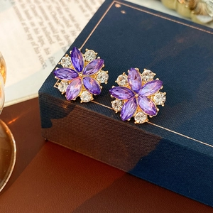 Dettaglio macro di orecchini a fiore vintage con cristalli viola e strass scintillanti