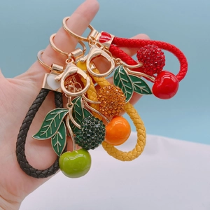 Detailed view of cherry keychains with rhinestones and colorful braided leather straps