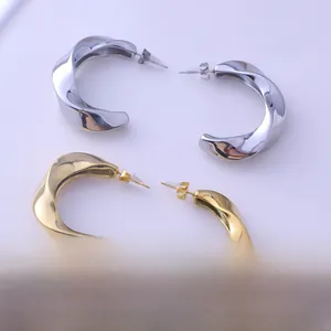 Polished gold and silver irregular liquid lava heart stud earrings on a round tray