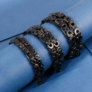 Detailed view of three black stainless steel punk chain bracelets on blue texture