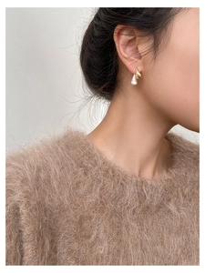 Detailed close-up of two-tone teardrop earrings with gold metal and pearl finish on model
