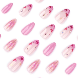 Pink French press-on nails in almond shape with heart patterns and sparkling rhinestones