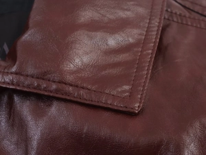 Dettaglio della trama in pelle PU rosso vino con cuciture doppie rifinite sulla giacca
