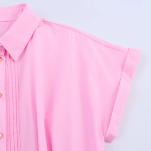 Detail of pink poplin shirt dress showing lapel collar and golden metal buttons