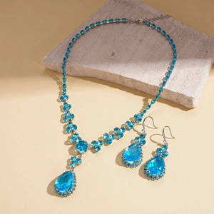 Detail of blue teardrop crystal necklace and matching earrings set on a stone prop