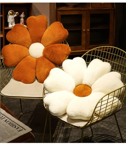 Close-up of orange and white flower-shaped plush pillows on golden iron chairs