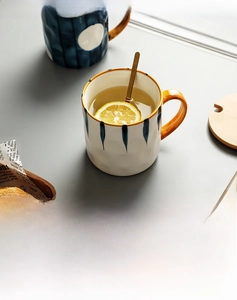 Macro shot of Japanese ceramic mug with blue stripes, gold handle and stirring spoon