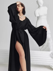 Detail of elegant black satin robe with flared sleeves and thigh-high side slit design