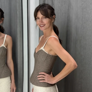 Brown tweed corset top with white lace trim and thin straps shown in mirror reflection
