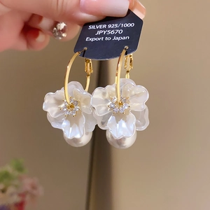 Macro detail of 925 silver flower earrings with pearls and crystals on price tag