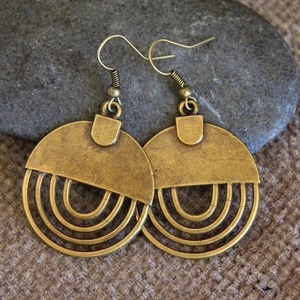 Vintage Bronze Ohrringe mit hohlem geometrischem Design auf rustikalem Leinenhintergrund