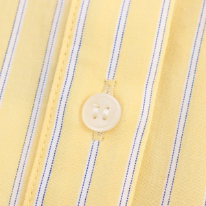 Close-up of blue yellow and white striped cotton dress fabric with white button detail