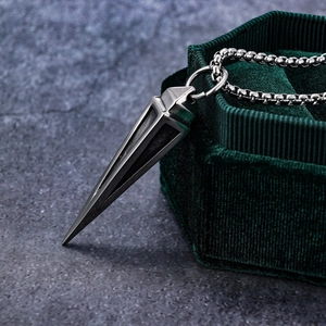 Macro shot of silver stainless steel triangle cone pendant on dark green velvet box edge