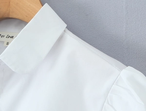 Close-up of white shirt detail showing the classic lapel and pleated puff sleeve design