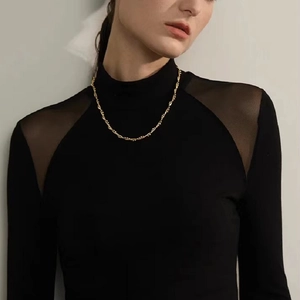 Golden stainless steel snake bead chain necklace with twisted vine design on female model