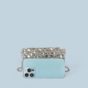 Close-up of silver metal floral woven crossbody bag with metallic chain strap detail