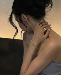 Close-up of gold plated star ring and colorful gemstone bracelet on model's hand
