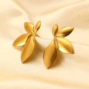 Close-up of golden leaf-shaped earrings on soft silk fabric with elegant metallic luster