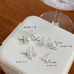 Detail view of four sizes of pearl stud earrings on a leather jewelry box lid