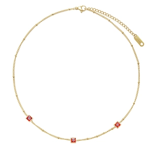 Détail du collier en acier inoxydable doré orné de trois cristaux rouges carrés